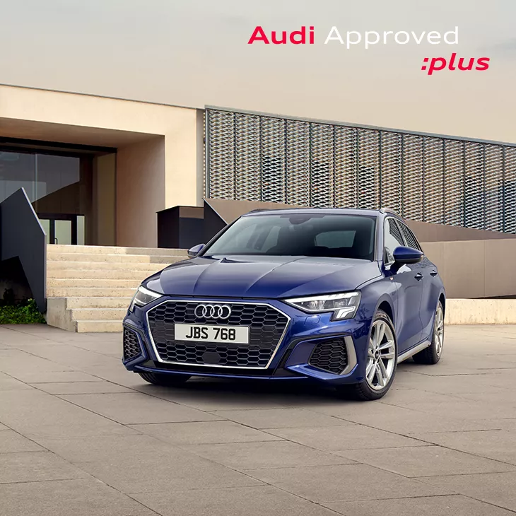 Blue Audi car parked in front of a modern building with "Audi Approved :plus" branding above