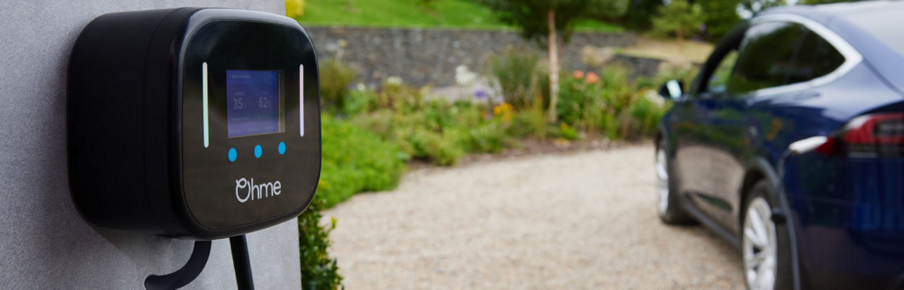 Electric vehicle charger mounted on wall with partially visible Audi vehicle in background