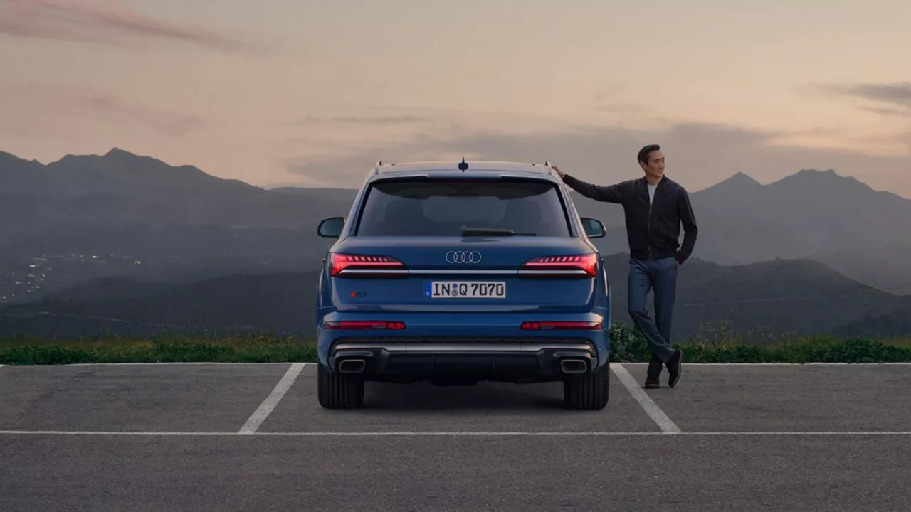 A man standing next to his Audi Q7 at Dusk