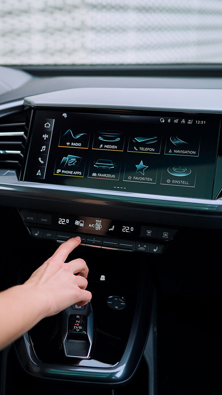 Eine Hand führt zur MMI eines Audi und klickt auf die Klimaanlage