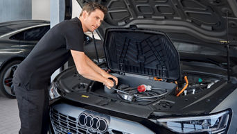 Mann hält seine Hände an ein Gerät im Motorraum eines Audi