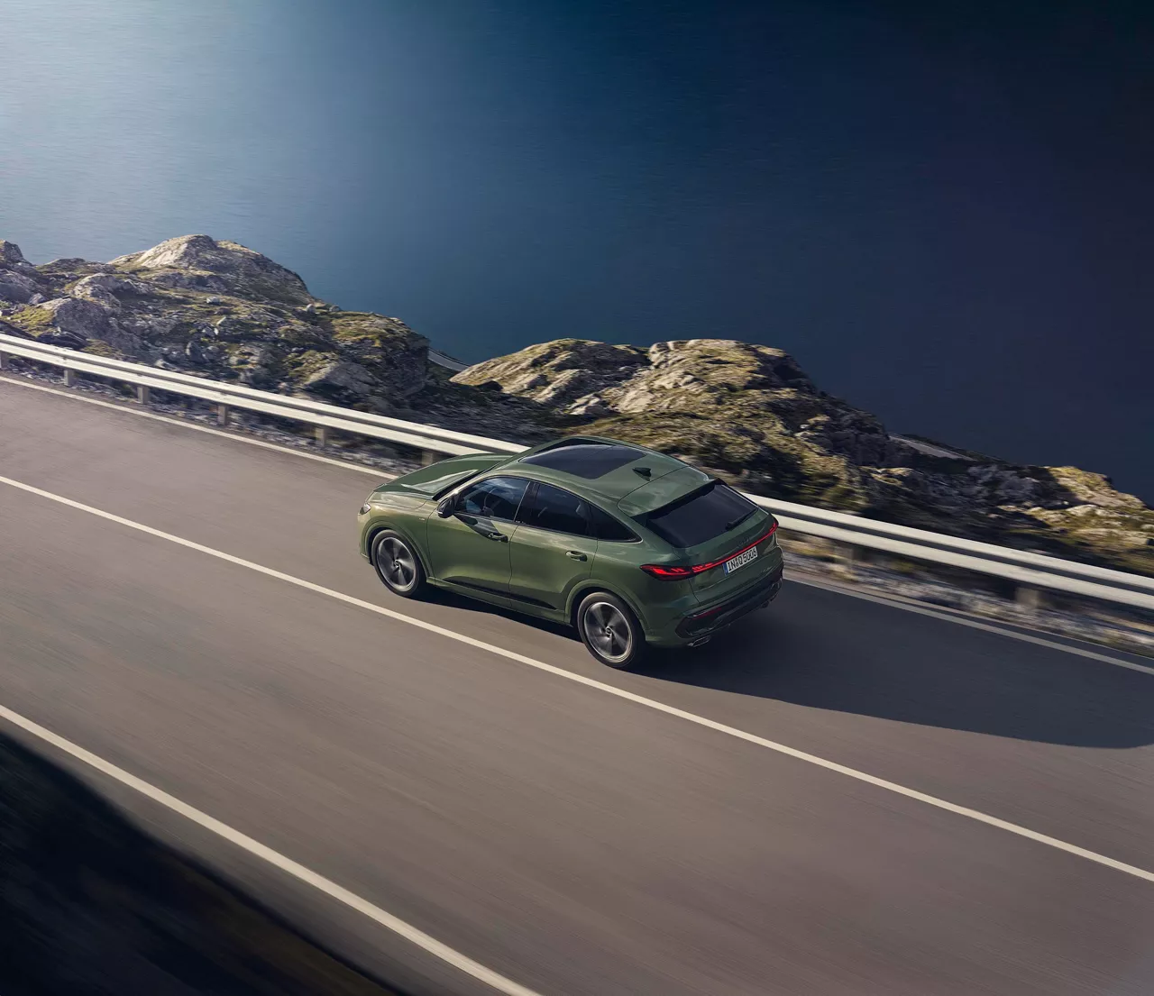 Grüner Audi Q5 fährt auf einer Autobahn neben dem Meer