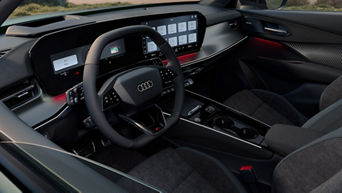 Innenraum eines Audi Modells mit schwarzem Lenkrad, großem Digitaldisplay und Ambiente-Beleuchtung in Rot.