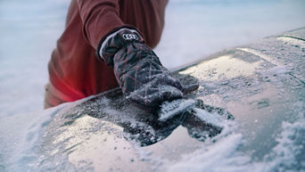 Eis wird mit dem Audi-Eiskratzer von der Autoscheibe entfernt.