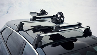 Snowboard mit Bindungen auf Dachträger eines Audi im Schnee befestigt.