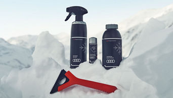 Audi Winterpflege-Set mit Enteiser, Glaspolitur, Frostschutz und Eiskratzer im Schnee.