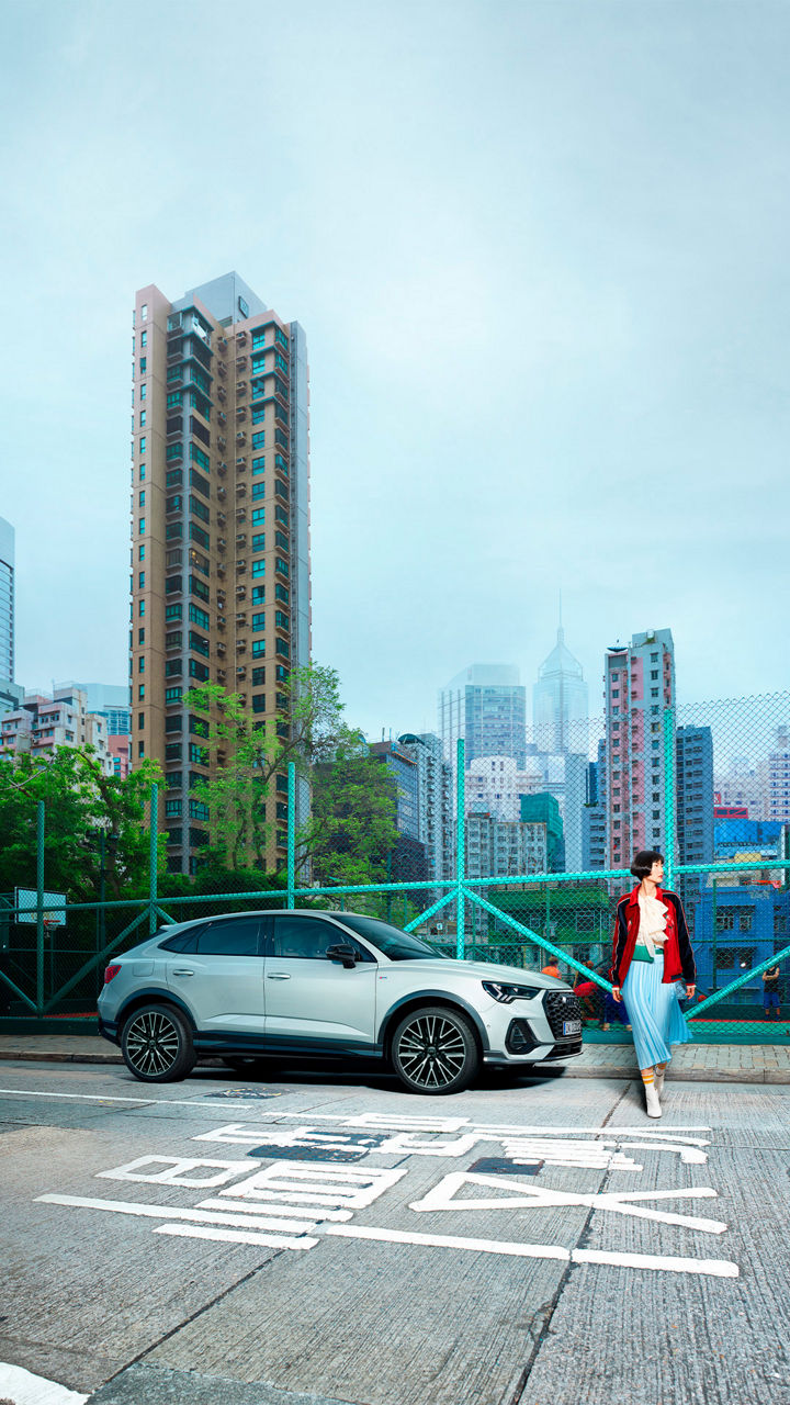 mujer caminando al lado de un Audi Q3 Sportback color gris